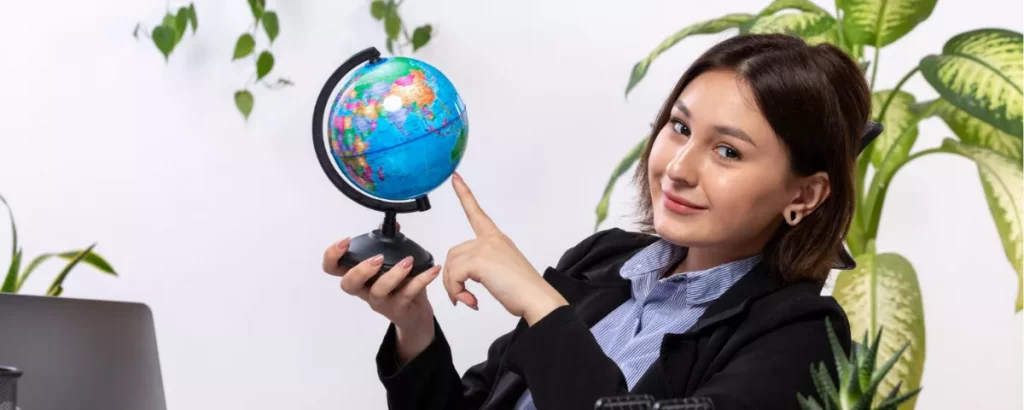 Une femme professionnelle tenant un globe terrestre de bureau, représentant la gestion des talents à l'échelle mondiale et les stratégies de recrutement international des RH.