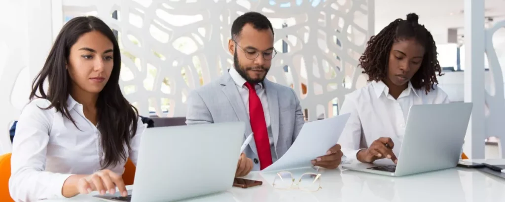 Collaborateurs en réunion d'affaires analysant des documents et des données chiffrées au sein d'un centre d'externalisation.