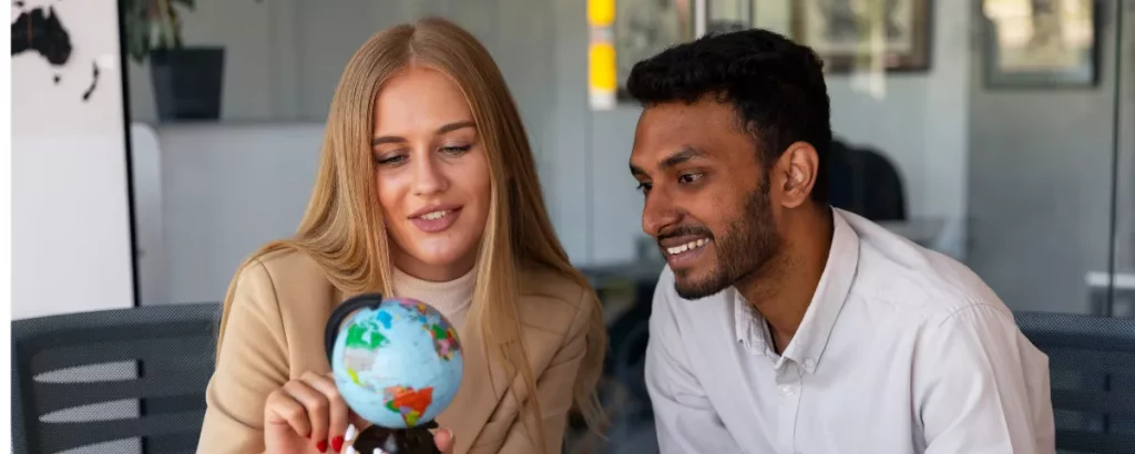Deux collaborateurs analysant un globe terrestre dans un bureau pour une stratégie d'externalisation.
