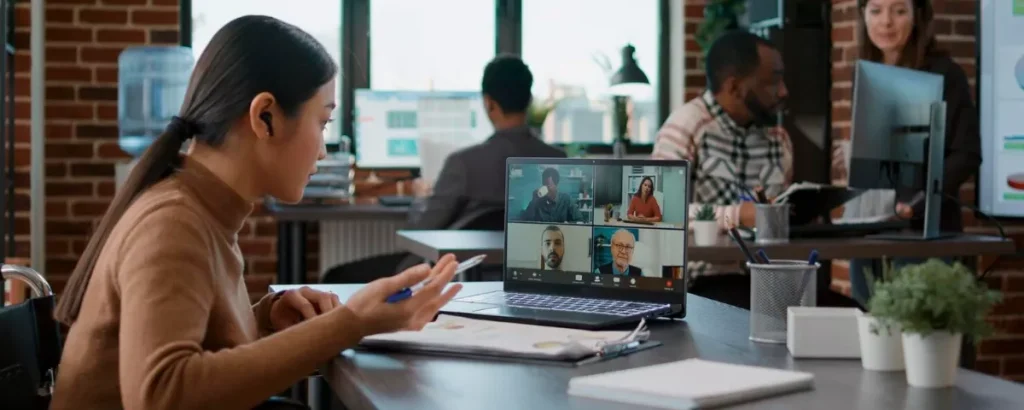 Échange professionnel en ligne sur ordinateur portable lors d'une session de formation et d'onboarding en télétravail.