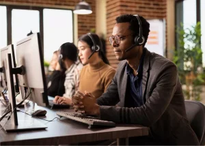 Agent de support client attentif devant son poste de travail lors de la gestion de demandes d'assistance.